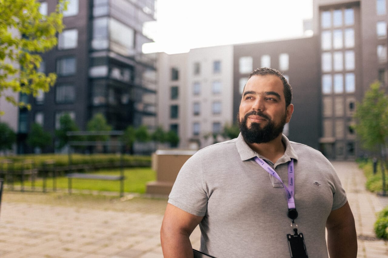 Kuvassa hymyilevä mies kerrostalon sisäpihalla.