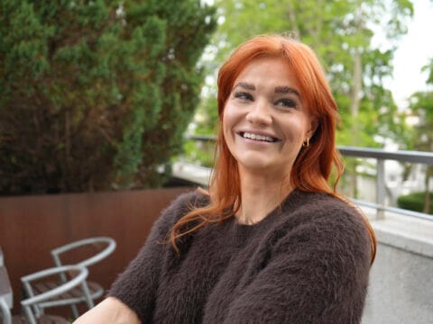 Lähikuva punatukkaisesta naisesta, joka hymyilee.