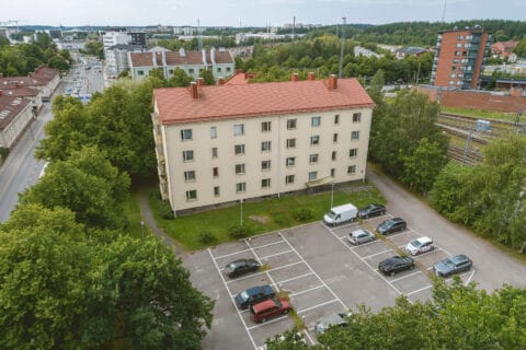 Kerrostalo ja parkkipaikka ilmasta käsin kuvattuna.